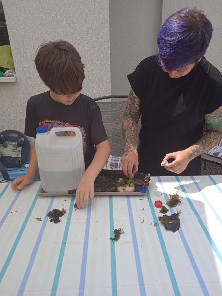 Yuma und Tina richten Steine und Moos in der Schale an
