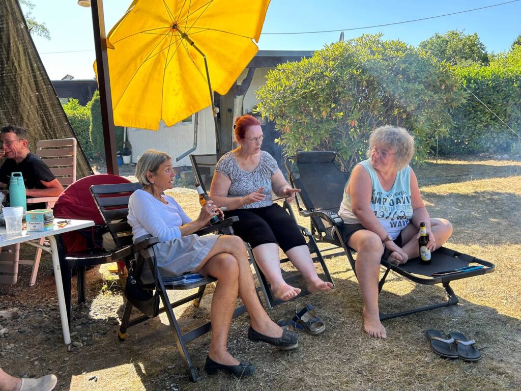 Drei Frauen entspannen in Liegestühlen unter einem gelben Sonnenschirm